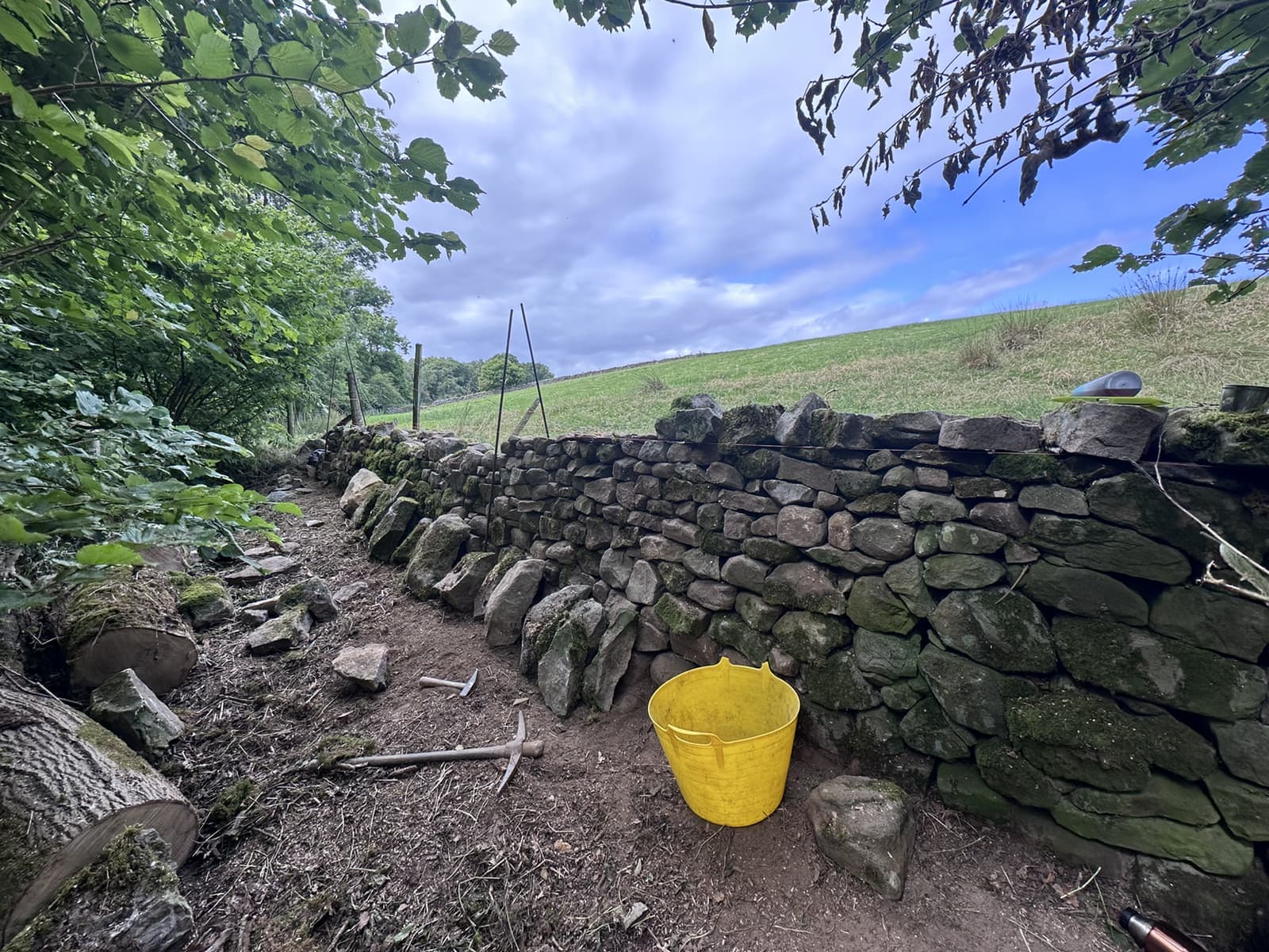 Traditional dry stone wall being rebuilt by hand in woodland